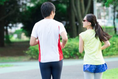 Sportif genç Asyalı çift parkta koşuyor.