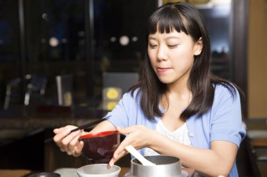 Kafede yemek yiyen genç Asyalı kadın. 