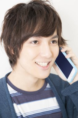 Duvarda akıllı telefondan konuşan genç adam.  