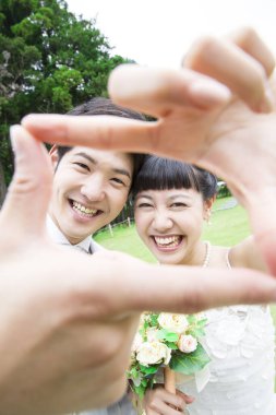 Elleriyle çerçeve yapan iki yeni evli genç. 