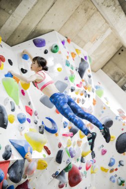 Sportif Asyalı kadın kaya duvarına tırmanıyor