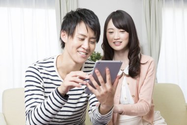 Mutlu Asyalı çift evde tablet kullanıyor.