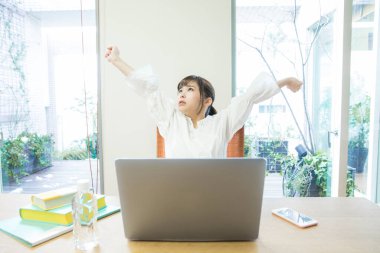 Dizüstü bilgisayarı olan genç bir kadın kollarını açıyor. 