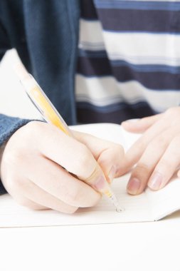 Adam deftere resim çiziyor, ellere yakın. 