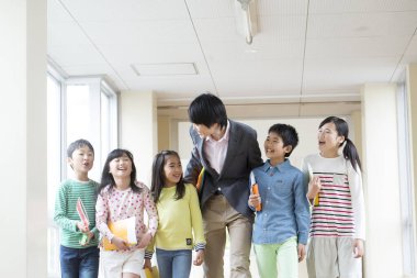 Öğretmenli bir grup Japon çocuk okul koridorunda yürüyor. 