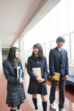 Lisede kitapları olan neşeli genç Japon öğrenciler.