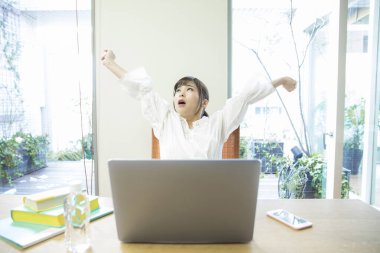 Dizüstü bilgisayarı olan genç bir kadın kollarını açıyor. 