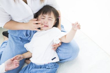 Ağlayan çocuk yetişkin bir kadın tarafından teselli ediliyor.