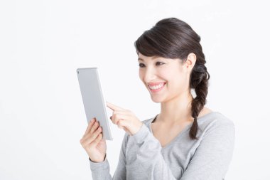 Tablet bilgisayar kullanan güzel bir Asyalı kadın.