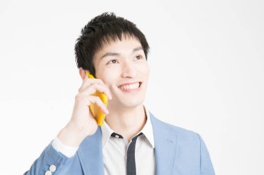 Genç Asyalı işadamı cep telefonuyla konuşuyor.