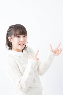 Beyaz kazaklı genç Japon kadın beyaz stüdyo geçmişini işaret ediyor.