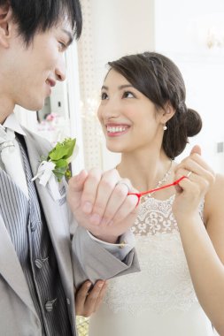 Güzel, mutlu, genç bir çift. Parmakları kırmızı iple bağlanmış. 