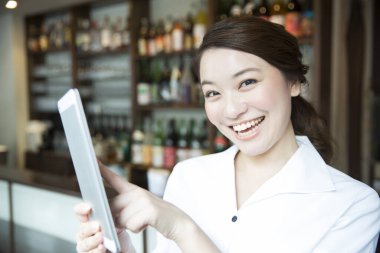 Restoranda tablet kullanan neşeli Asyalı garsonun portresi