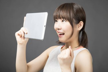 Gri arkaplanda dijital tabletli genç Asyalı kadın izole edilmiş. 