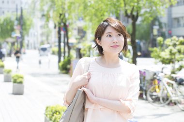 Şehirde çantalı bir kadın yürüyor.