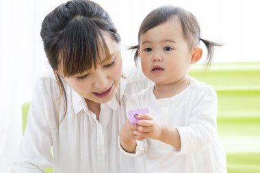 Evdeki oturma odasında genç annesiyle oynayan tatlı bir Japon kızı.