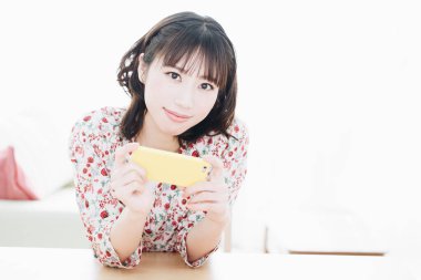 Akıllı telefon kullanan gülümseyen Asyalı genç kadının portresi 