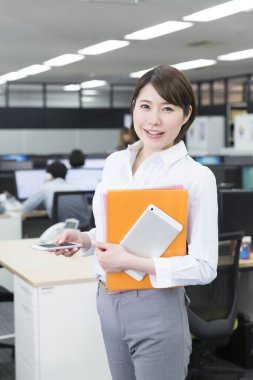 Modern ofiste akıllı telefonu olan genç bir iş kadını.