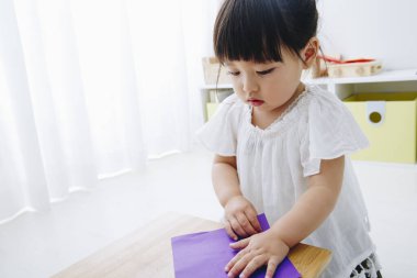 Küçük tatlı Japon kız oturma odasında oyuncaklarla oynuyor.