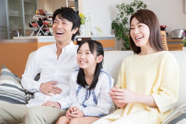 Genç bir aile kanepede oturup televizyon seyrediyor.