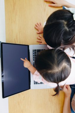 Asyalı tatlı kızlar evde dizüstü bilgisayarla oynuyorlar. 