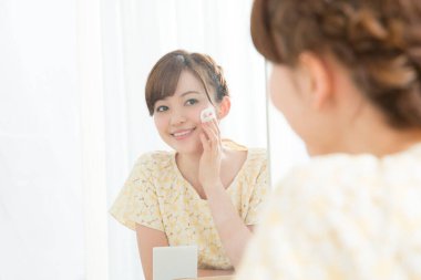 Güzel Asyalı kadın yüz pudrası yapıyor. 