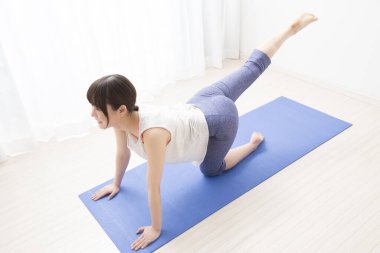 Genç Asyalı kadın evde yoga yapıyor.