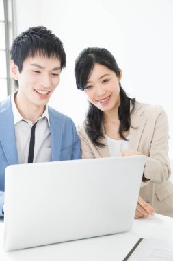 Genç işadamı ve iş kadını dizüstü bilgisayarda birlikte çalışıyorlar.