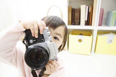 Küçük kız kamerayı evde tutuyor.