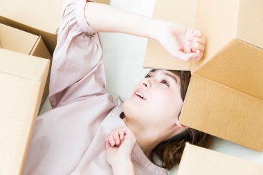 Genç bir kadın yerde yatıyor ve karton kutuları açıyor..