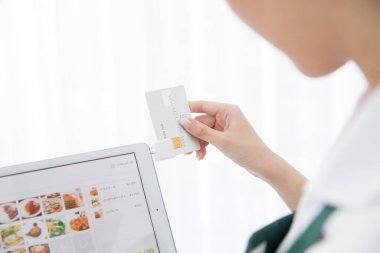 Kadın kredi kartıyla online ödeme yapmak için banka kartını kullanıyor.