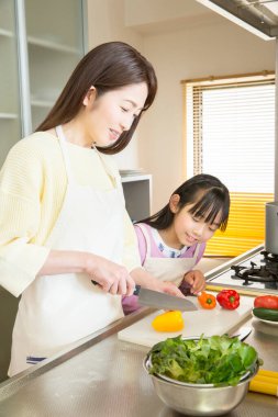 Genç anne ve kız mutfakta taze salata hazırlıyorlar. 