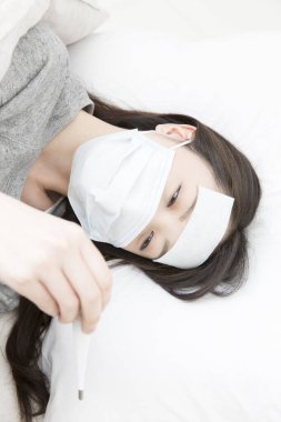 Ateşli genç Asyalı kadın yatakta yatıyor.