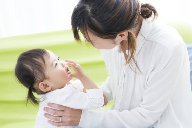 Evdeki oturma odasında genç annesiyle oynayan tatlı bir Japon kızı.