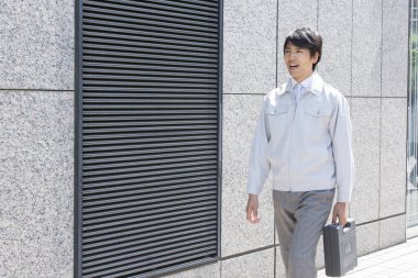 Yakışıklı profesyonel Japon işadamı evrak çantası tutuyor ve sokakta yürüyor.    