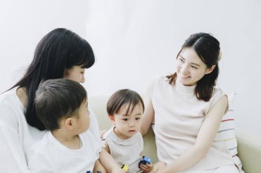 Neşeli Asyalı anneler ve çocuklar oturma odasında oynuyor.