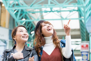 İki mutlu Asyalı arkadaş şehirde yürürken yukarı bakıyor..