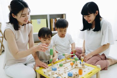 Çocuklarla evde oynayan gülümseyen Asyalı anneler