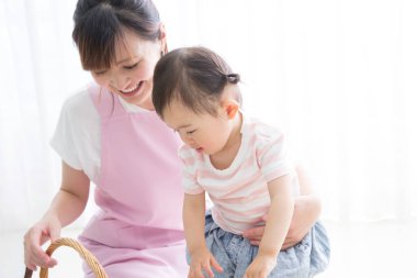 Genç Asyalı anne ve küçük kızı sepetlerle oynuyorlar. 