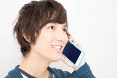 Duvarda akıllı telefondan konuşan genç adam.  