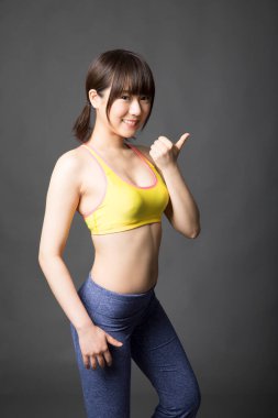 Başparmak gösteren Asyalı genç kadın.