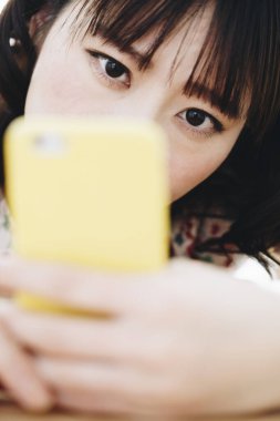 Evde akıllı telefon kullanan güzel bir Asyalı kadın.