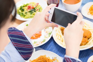 close - up of woman taking a photo of food on smart phone