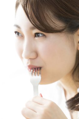 Genç Asyalı kadın yemek yiyor.