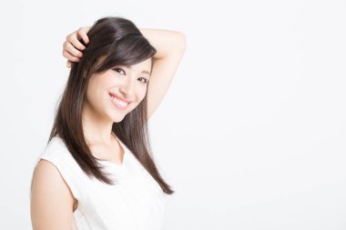 Genç Asyalı kadın gülümsüyor ve koltuk altını gösteriyor.