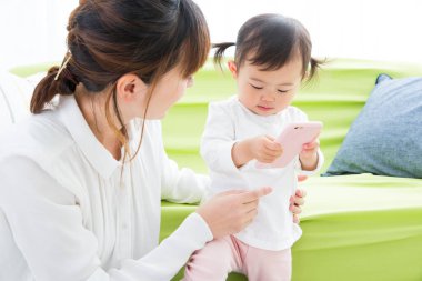 Evdeki oturma odasında genç annesiyle oynayan tatlı bir Japon kızı.