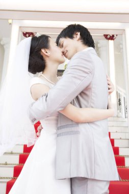 Mutlu Asyalı gelin ve damadın öpüşme portresi