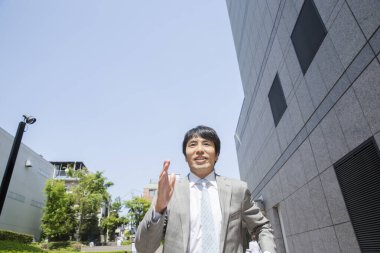 Yakışıklı profesyonel Japon iş adamı sokakta koşuyor.   