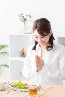 Genç Japon kadın mutfakta yemek yiyor.