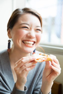 Restoranda pizza yiyen kadın.